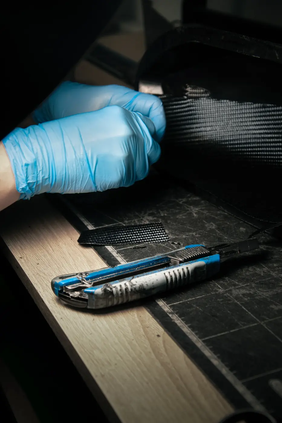 Un tecnico manipola uno strato di prepreg in fibra di carbonio durante la preparazione della laminazione manuale